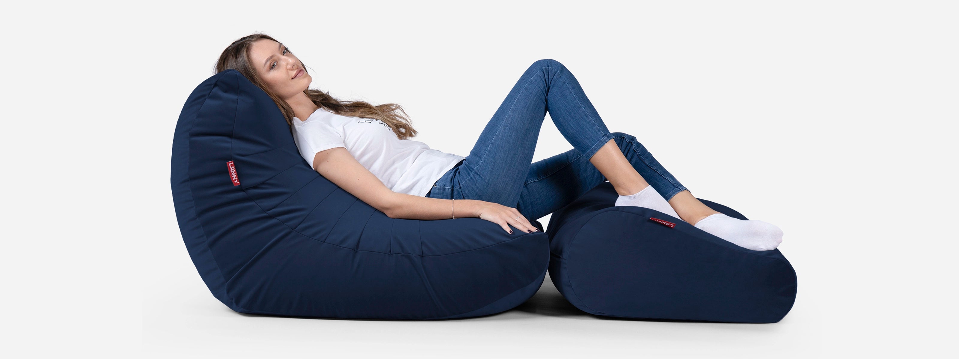 Woman sitting on a navy bean bag chair against a white background