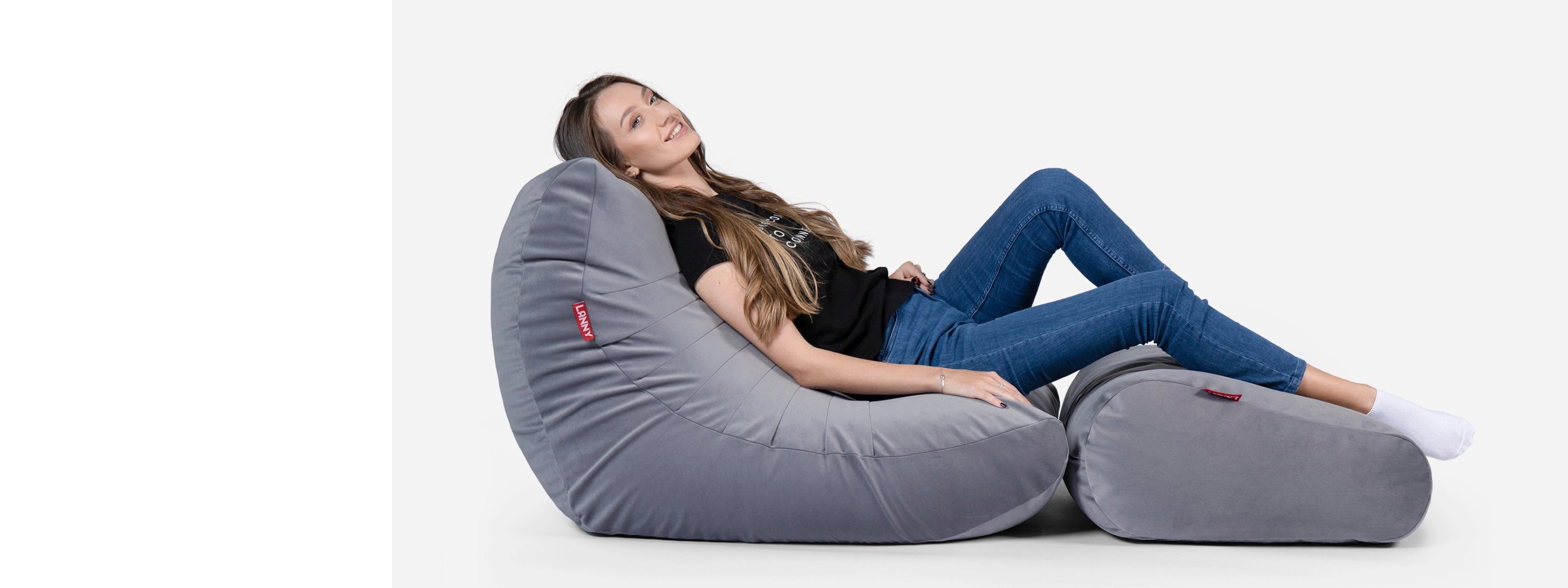 Woman sitting on a Lanny  large gray bean bag chair against a white background