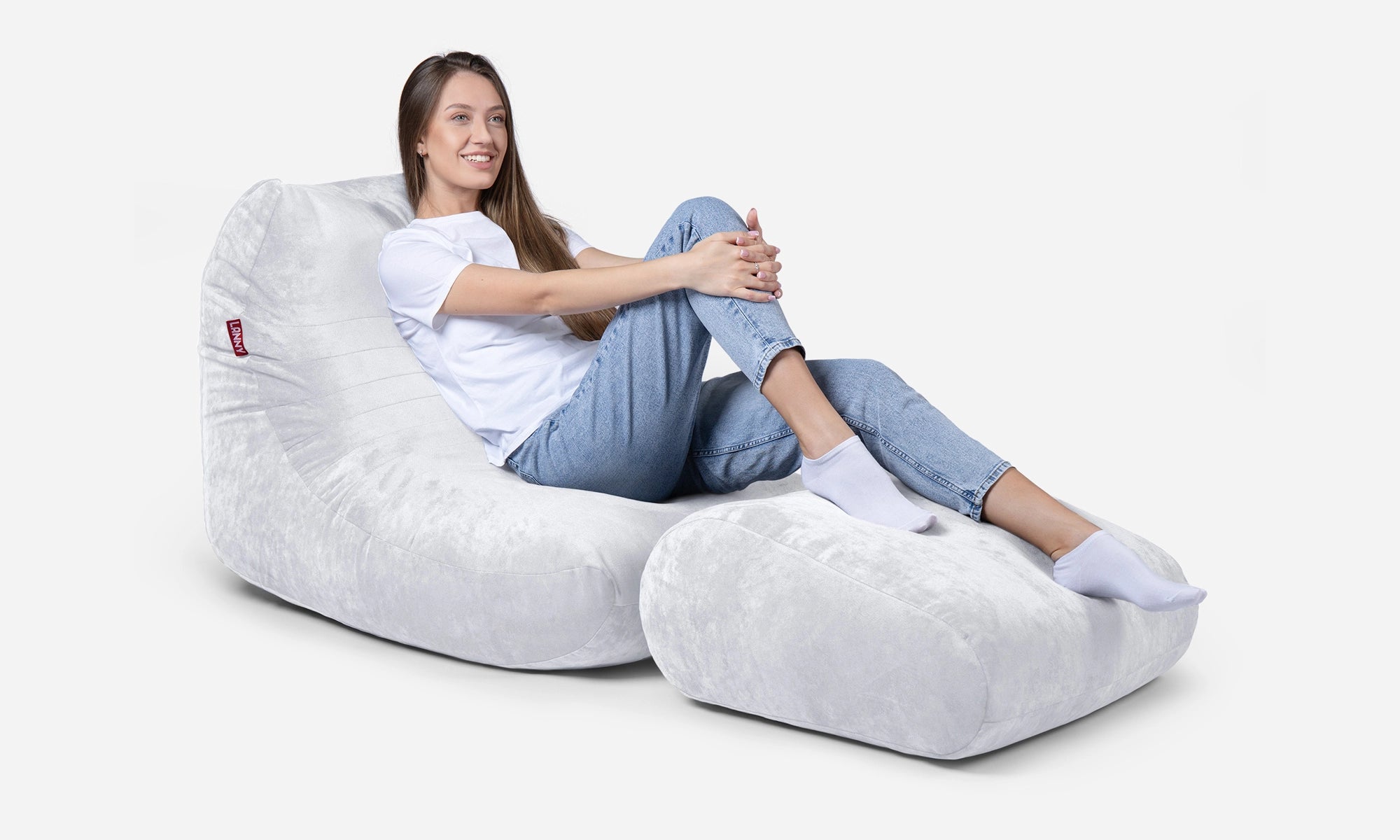 Person sitting on a Lanny curvy bean bag chair and footrest with a white background