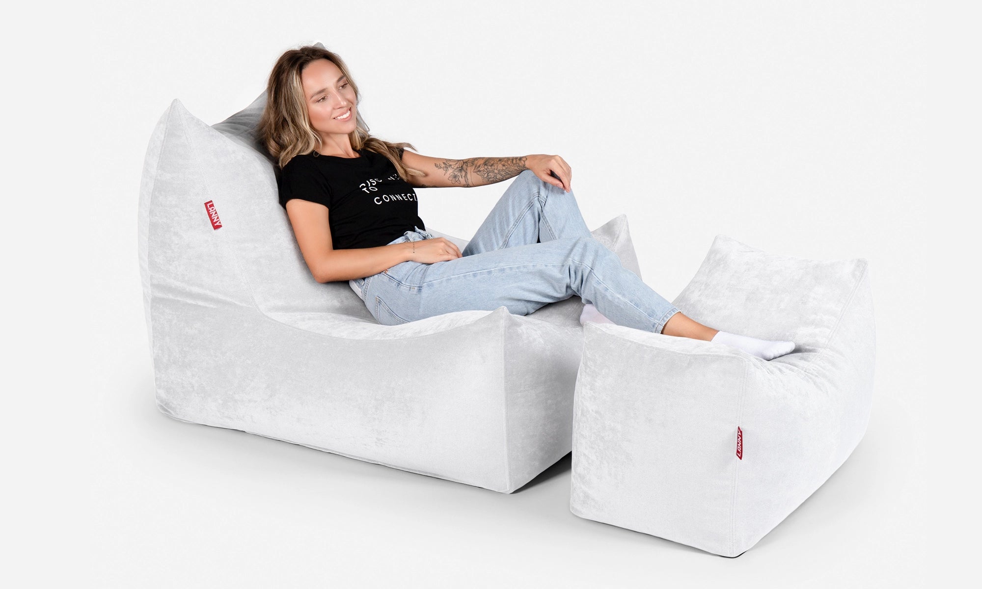 Person sitting on a Lanny Quadro white bean bag chair and footrest with a plain background