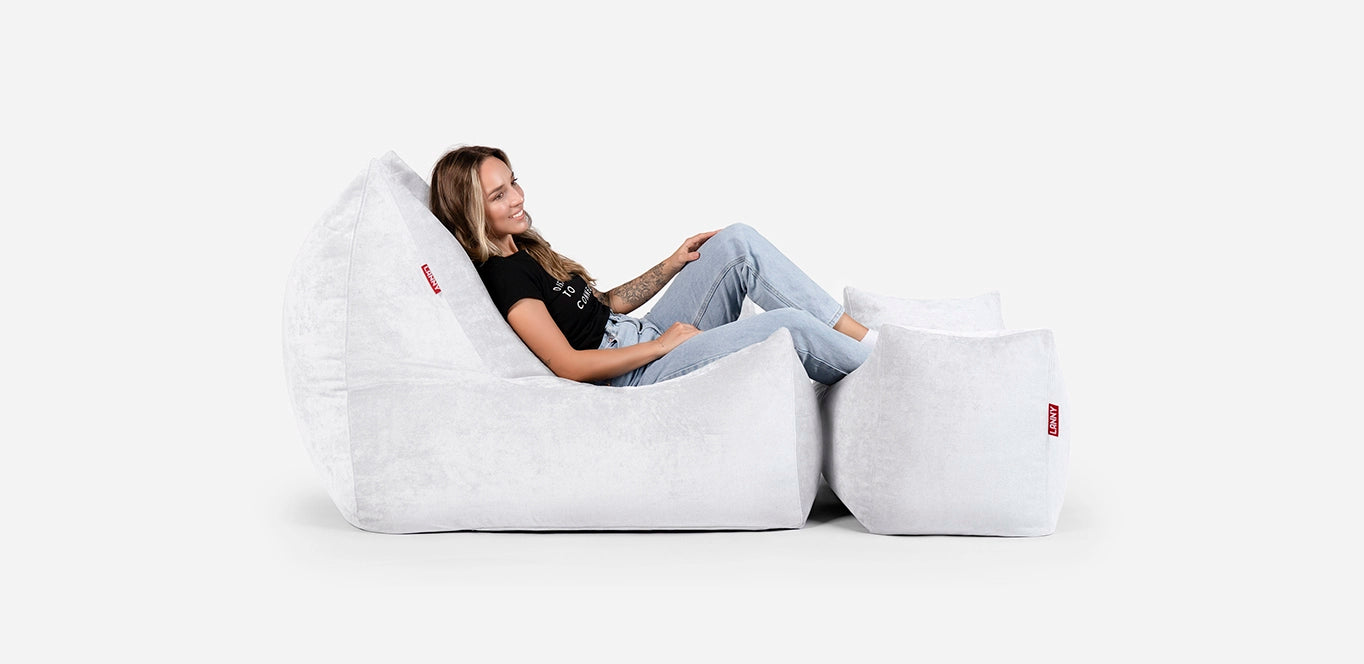 Person sitting on a Lanny large white bean bag chair with footrest against a white background