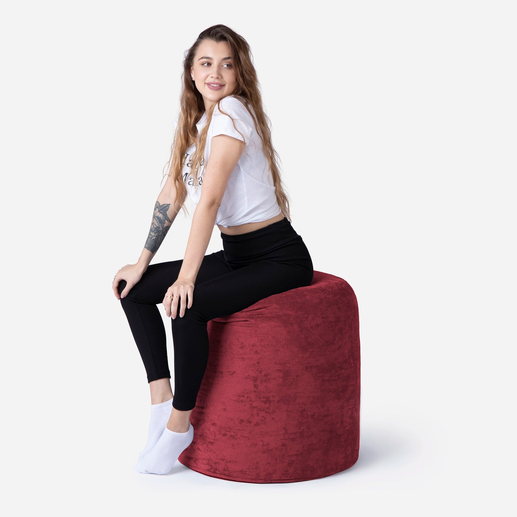 Woman sitting on a Tall red Pouf against a white background