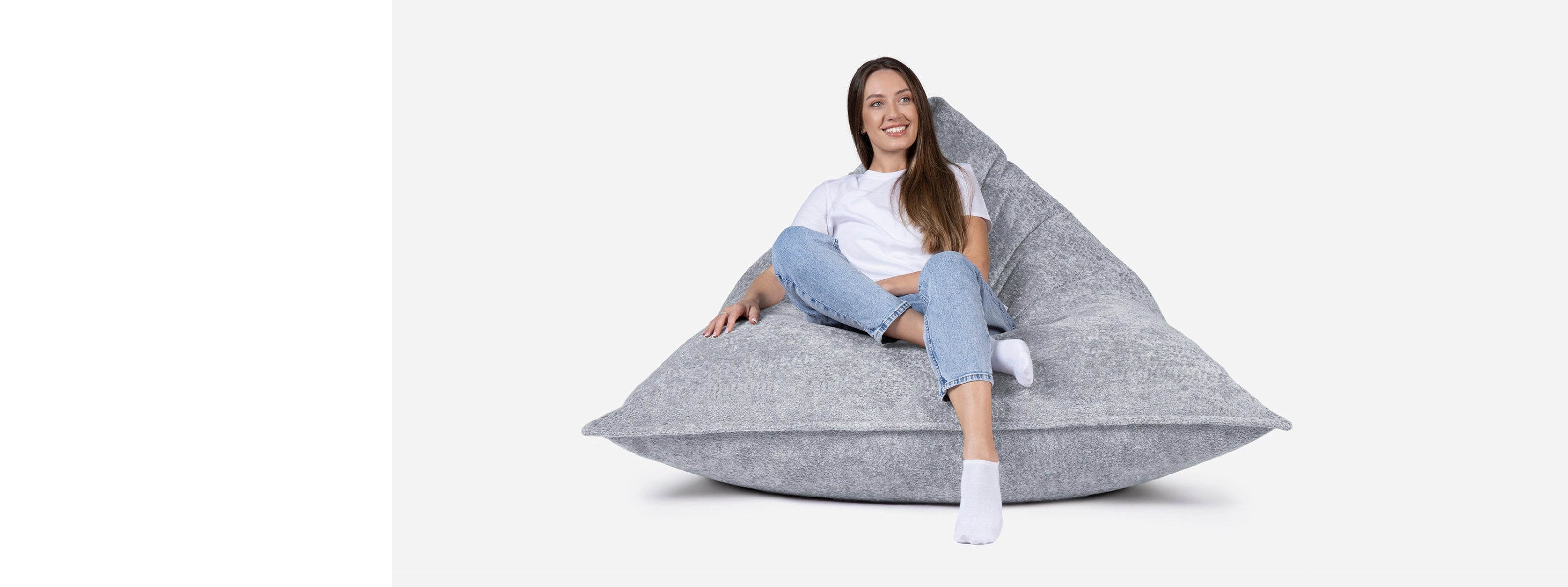 Woman sitting on a Lanny large gray bean bag chair against a white background