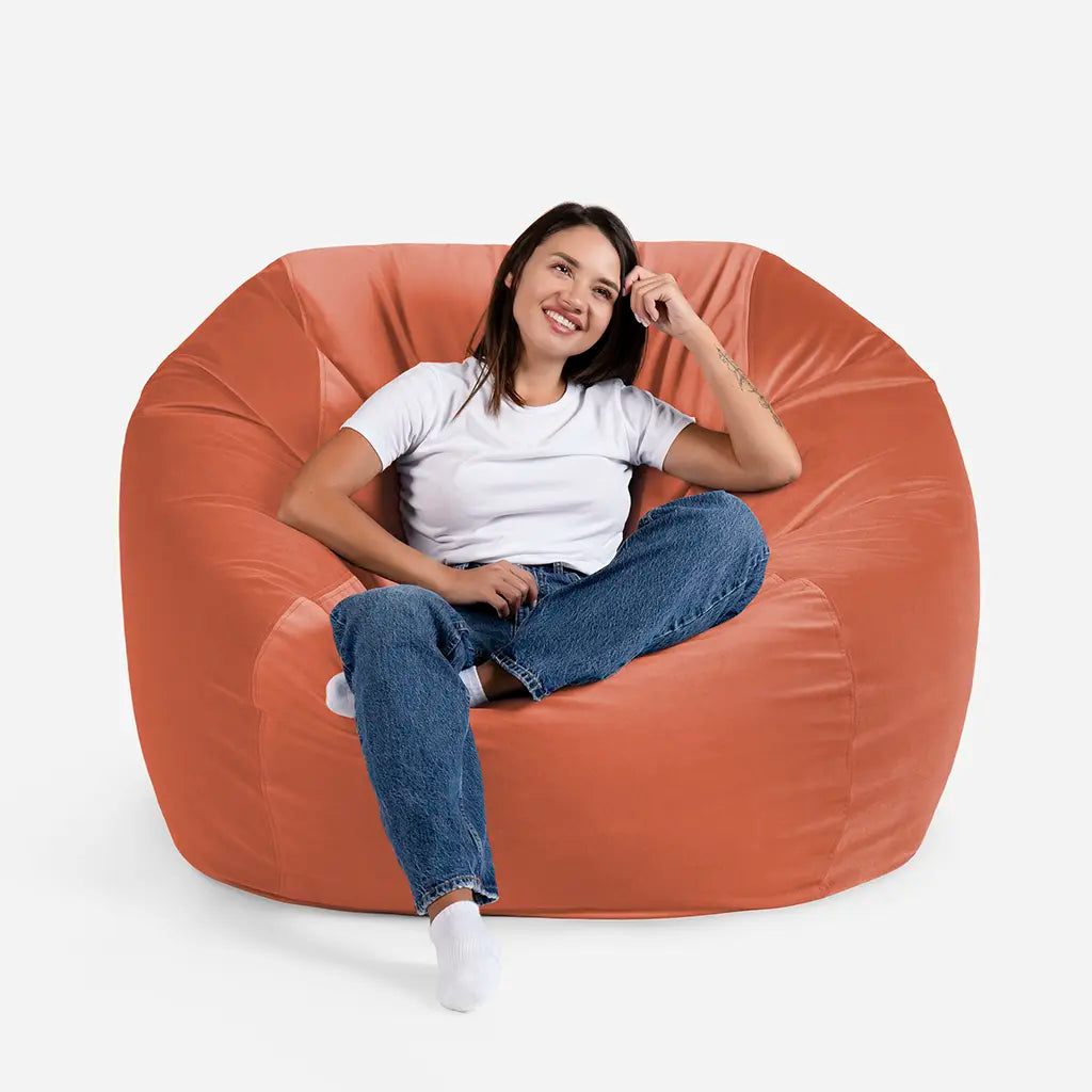 Woman sitting comfortably on a Lanny Sphere oversized velvet bean bag chair in Amber orange color for UAE living room seating