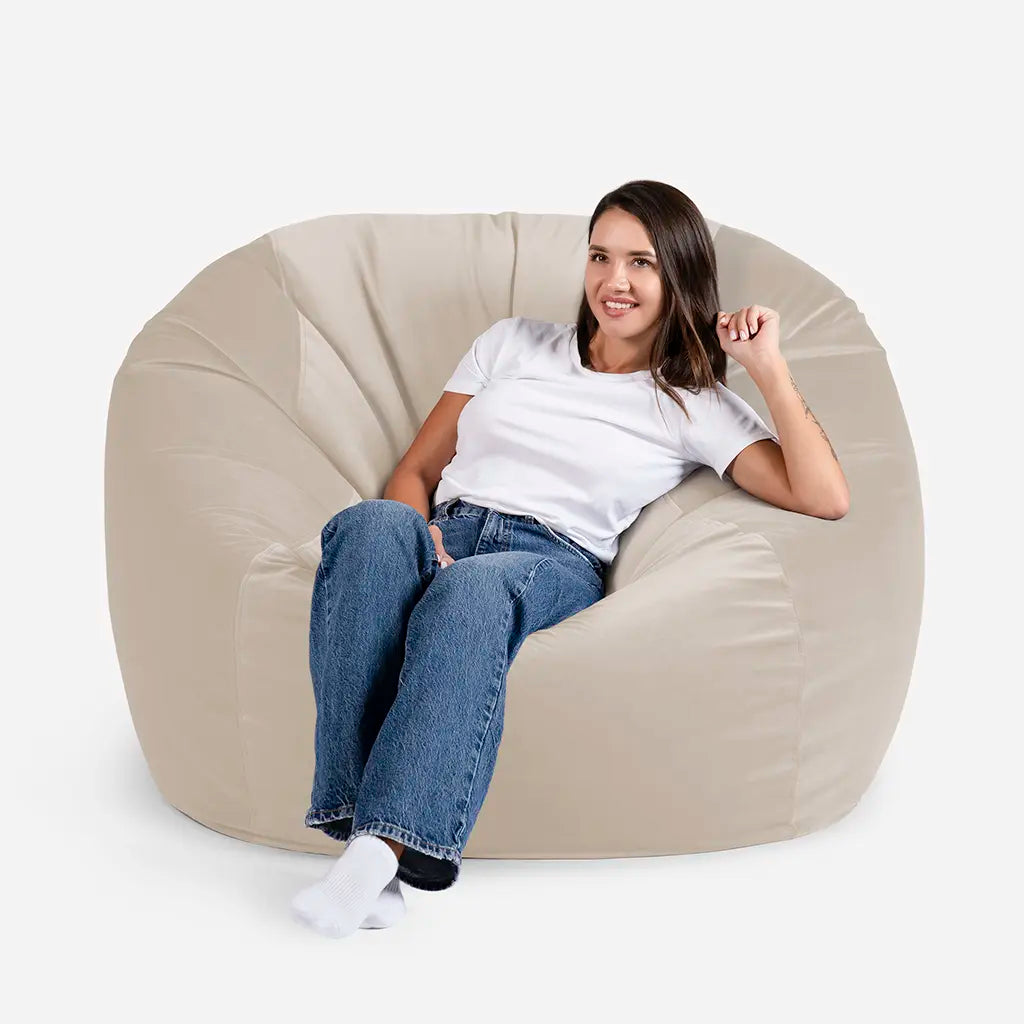 Woman sitting comfortably on a Lanny Sphere oversized velvet bean bag chair in Beige color for UAE living room seating