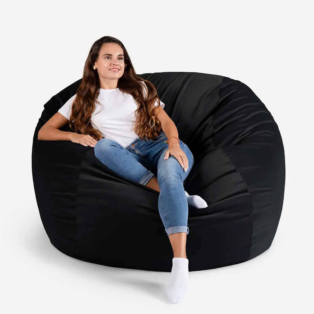 Woman sitting comfortably on a Lanny Sphere oversized velvet bean bag chair in black color for UAE living room seating