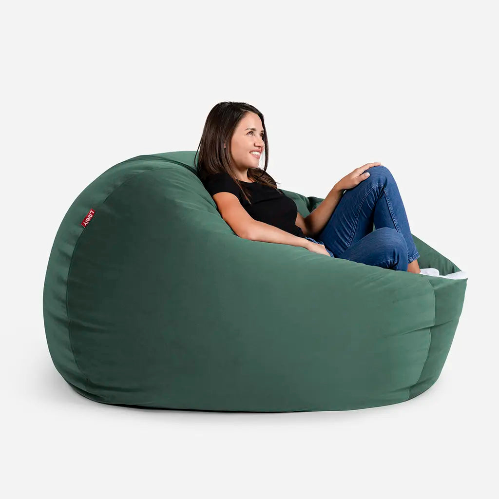 Woman relaxing on a Lanny Sphere green velvet bean bag chair, showing the large size and comfortable back support