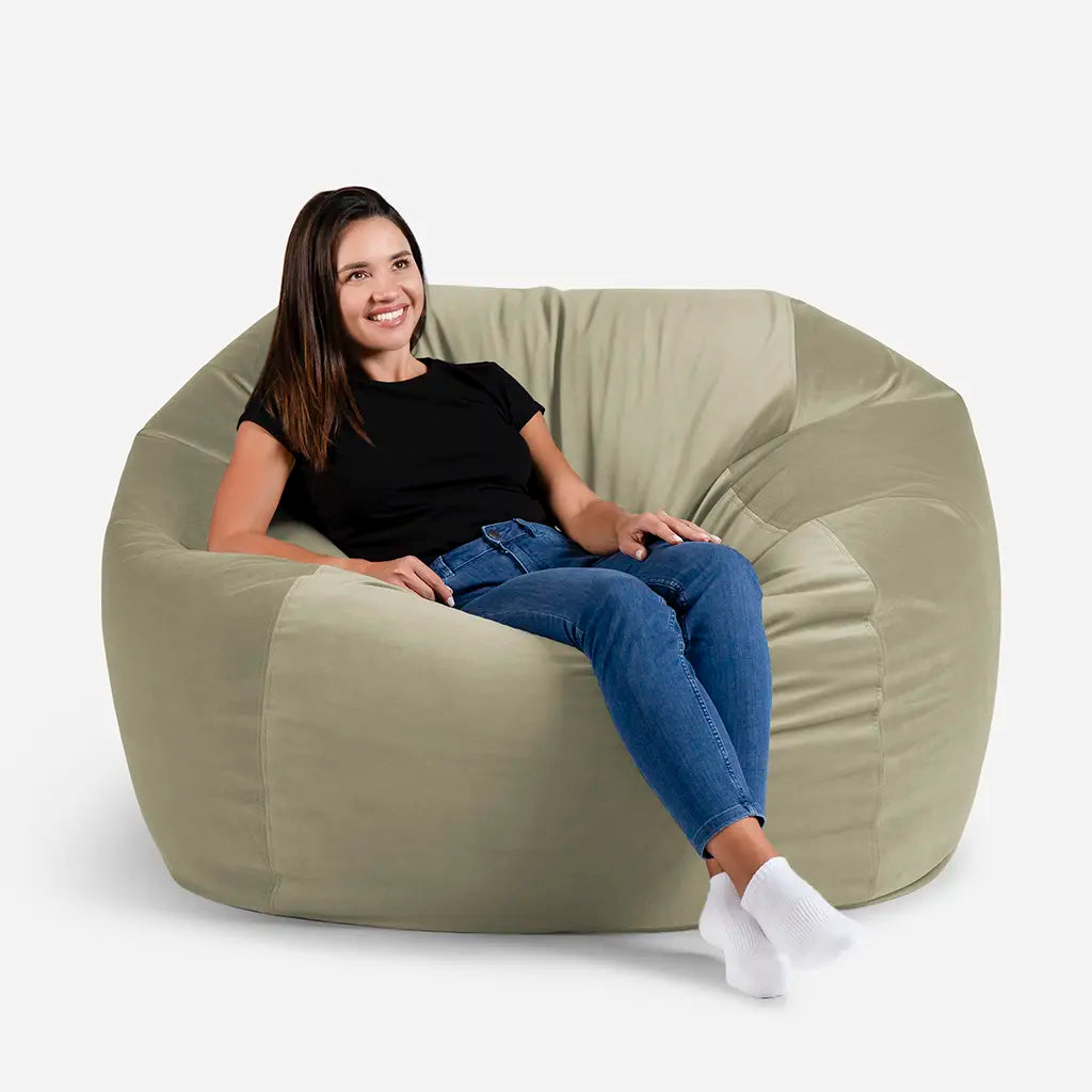 Woman sitting comfortably on a Lanny Sphere oversized velvet bean bag chair in Khaki green color for UAE living room seating
