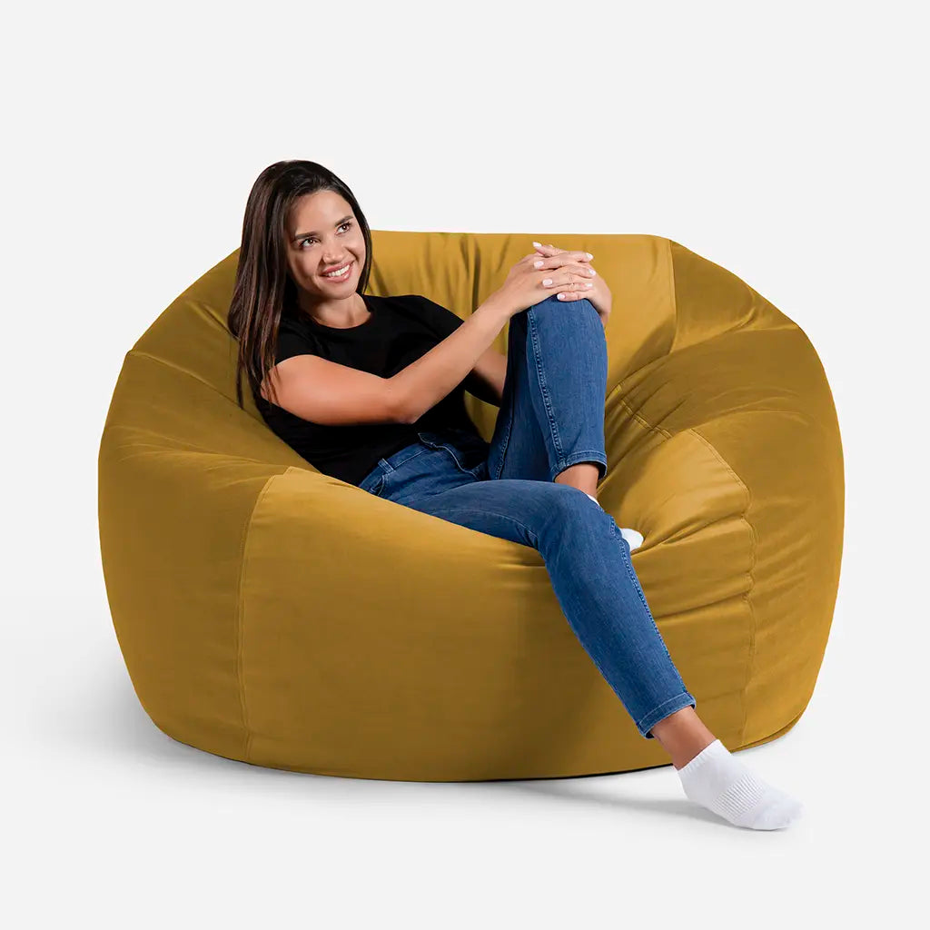 Woman sitting comfortably on a Lanny Sphere oversized velvet bean bag chair in Mustard color for UAE living room seating