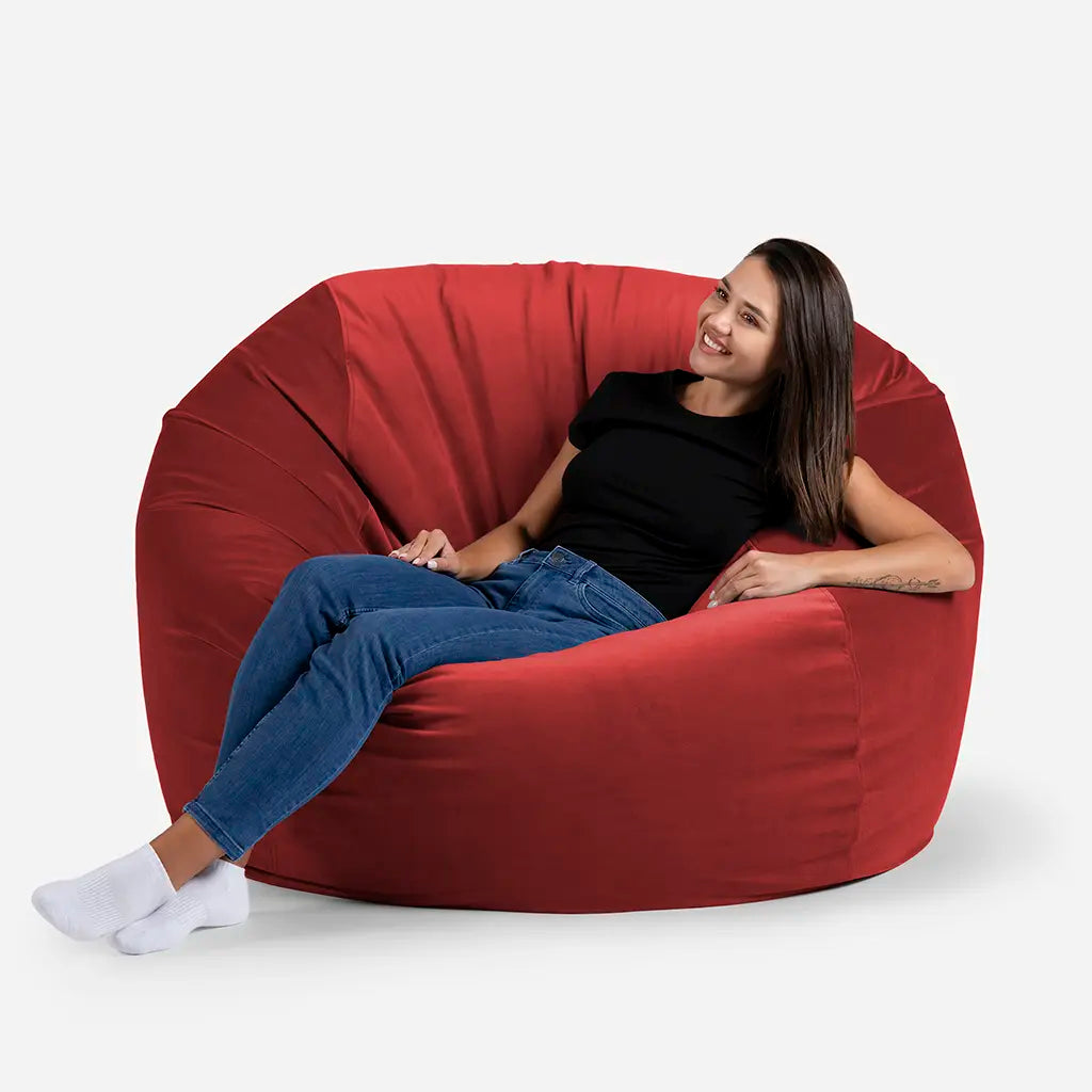 Woman sitting comfortably on a Lanny Sphere oversized velvet bean bag chair in Red color for UAE living room seating