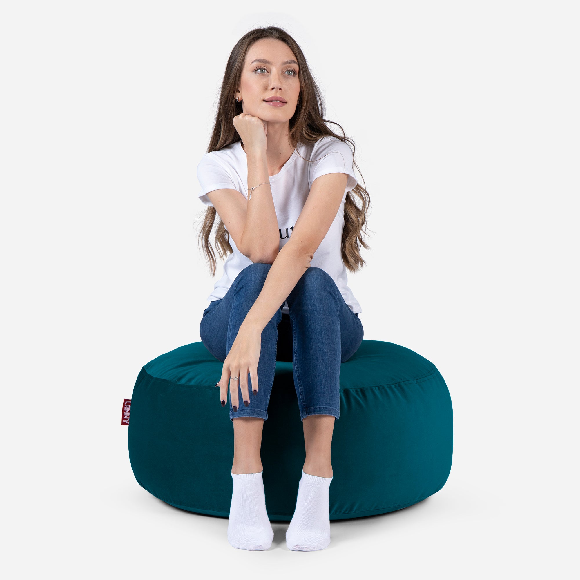 girl siting on Lanny pouf made from velvet fabric in aqua color