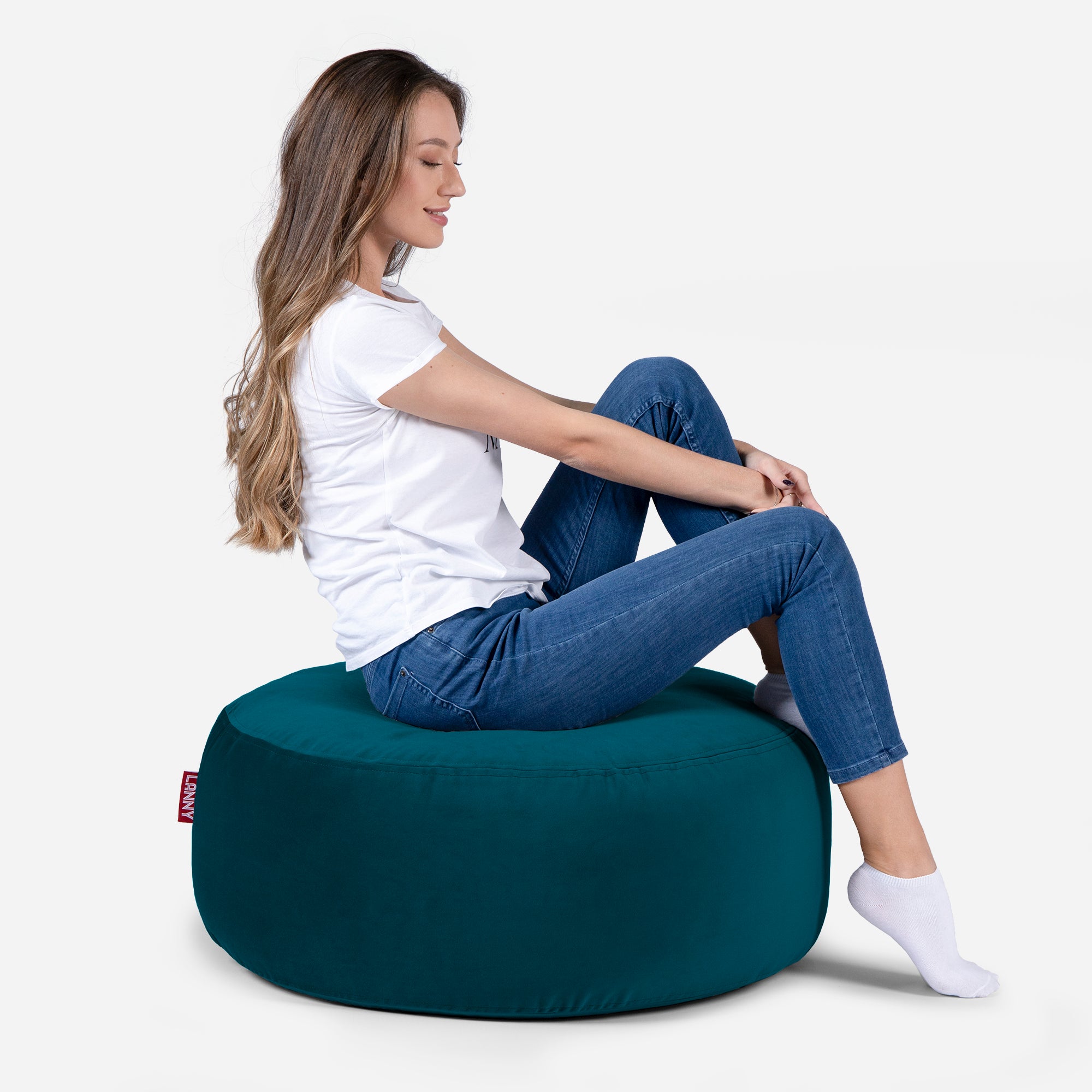 girl siting on Lanny pouf made from velvet fabric in aqua color