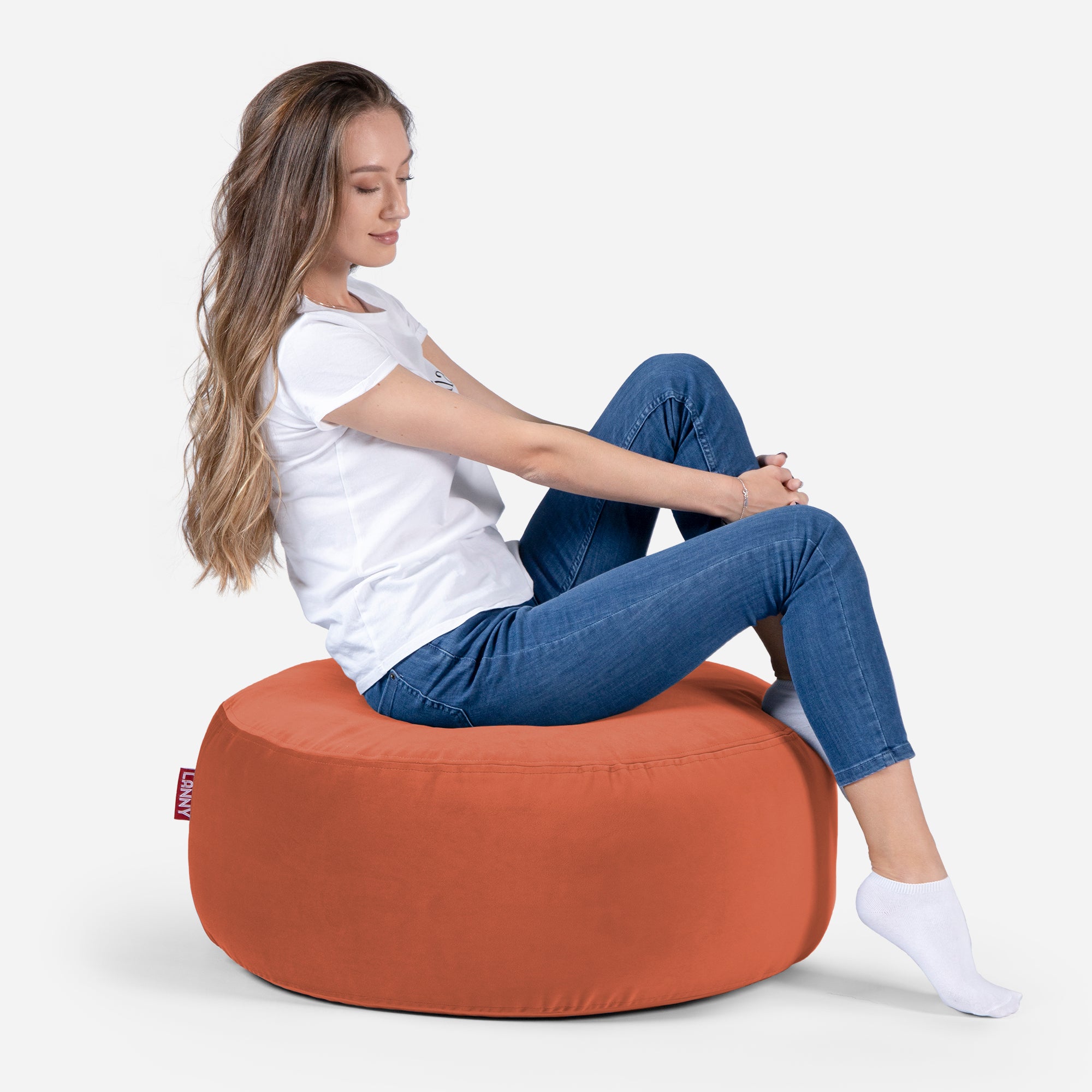 girl siting on Lanny pouf made from velvet fabric in orange color