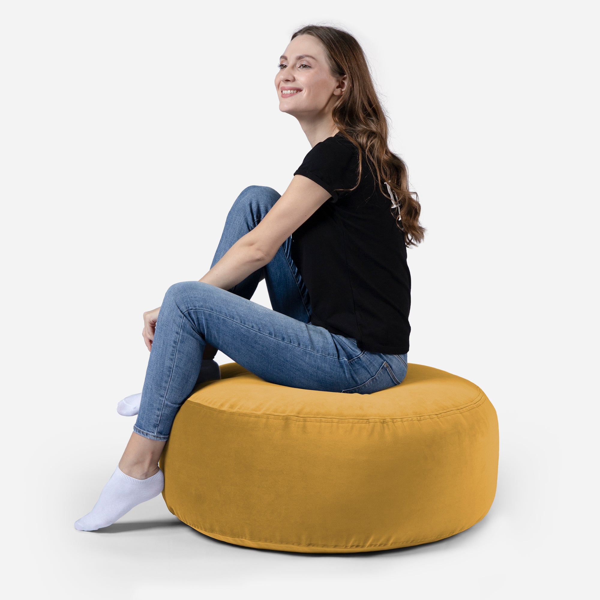 girl siting on Lanny pouf made from velvet fabric in Mustard color