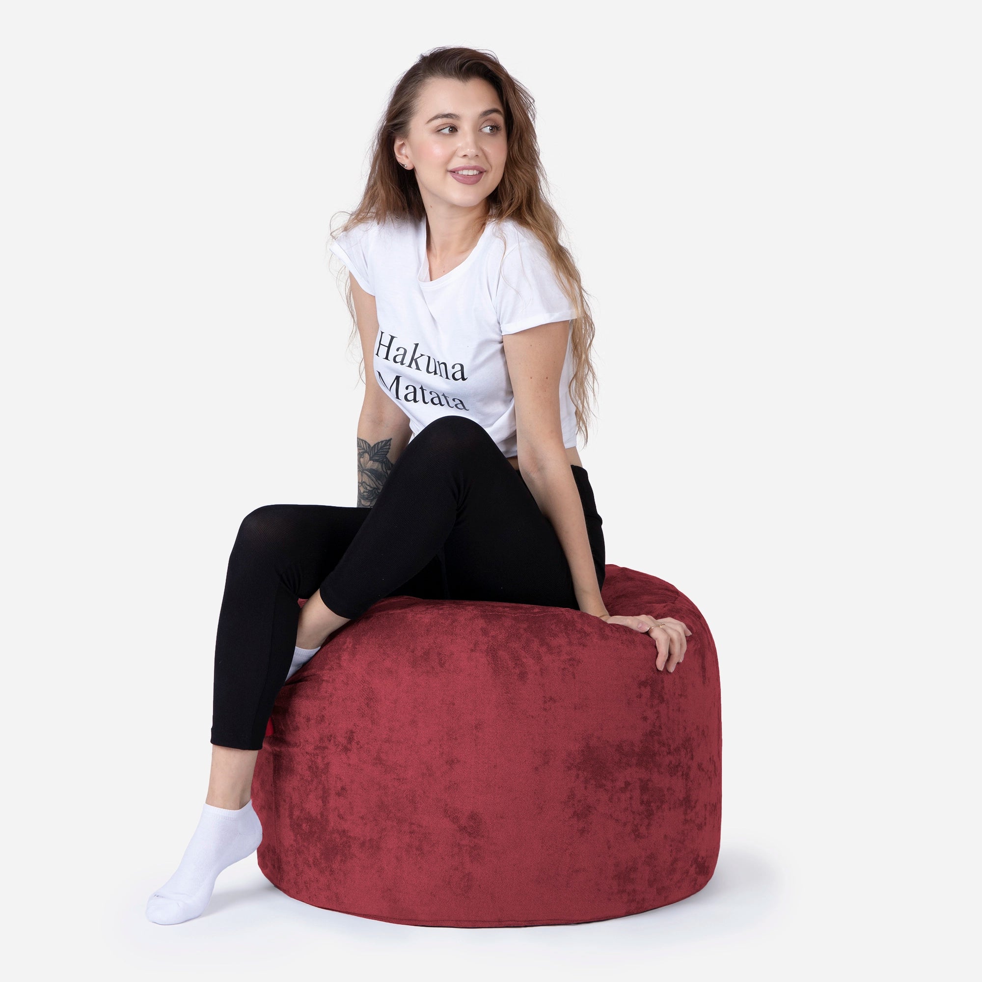 Woman sitting on a red Medium size pouf chair wearing a white t-shirt with text.
