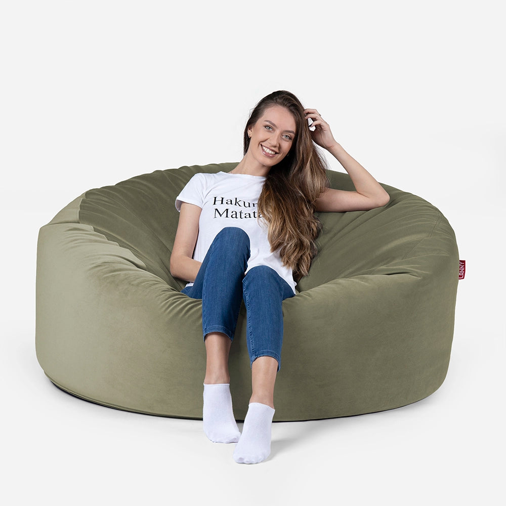 Woman sitting on a Lanny Original large green bean bag chair against a white background