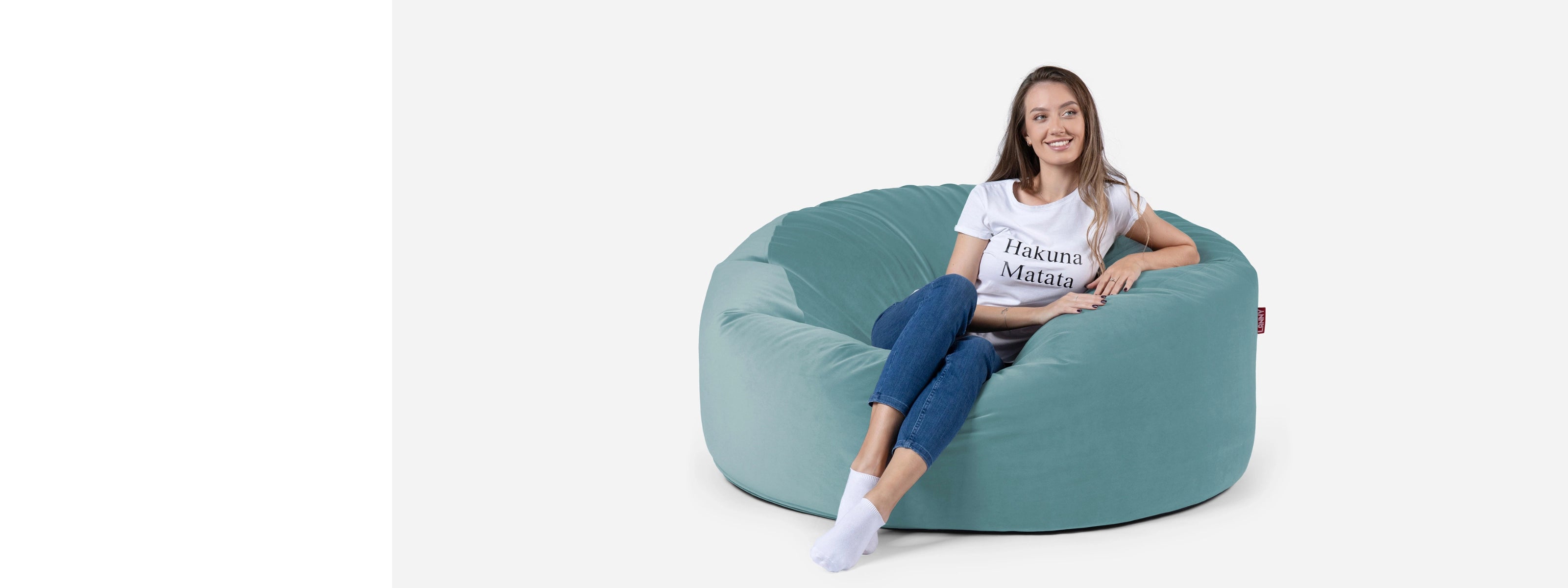 Woman sitting on a Lanny round-shaped bean bag chair against a white background