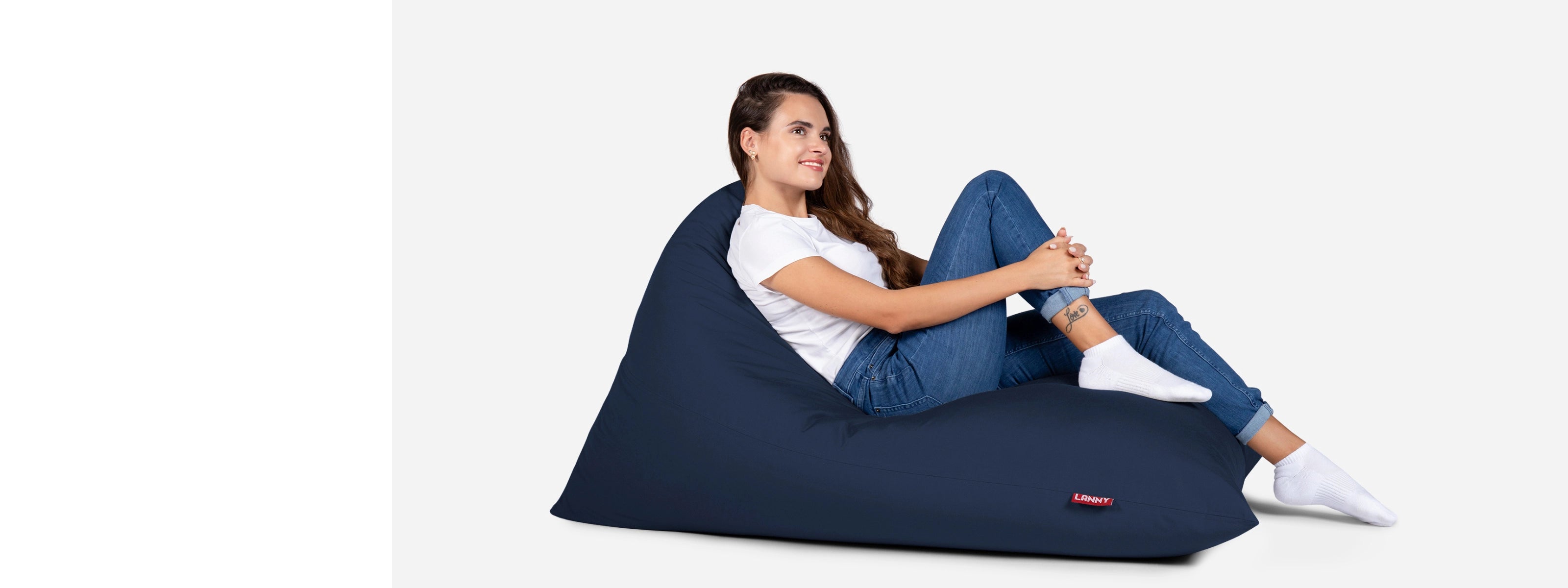 Woman sitting on a Lanny navy bean bag chair against a white background