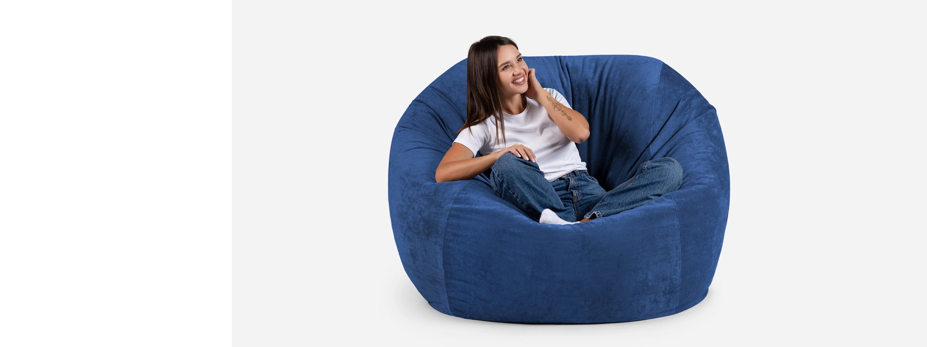 Woman sitting on a Lanny large blue bean bag chair against a white background