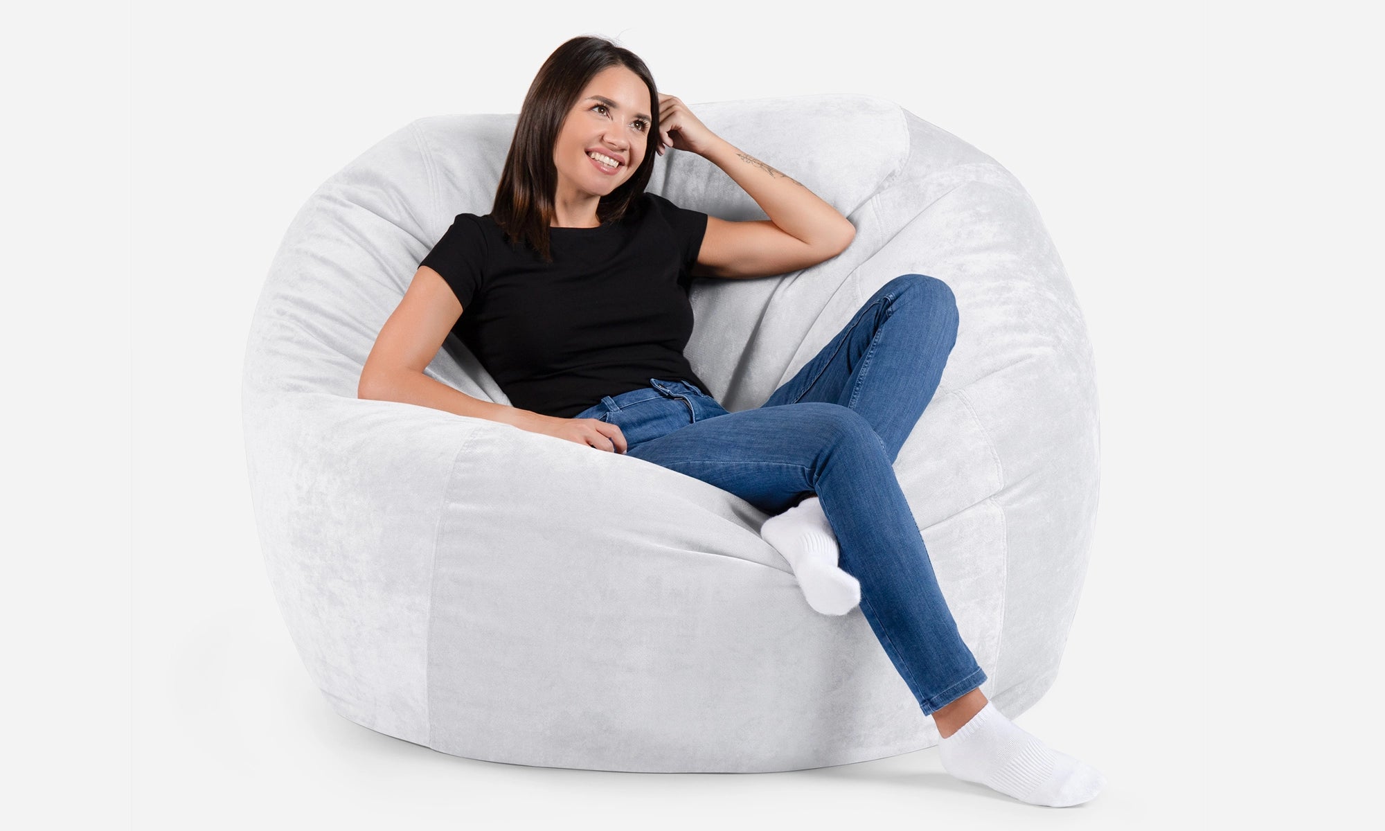 Woman sitting on a white Lanny sphere  bean bag chair against a white background