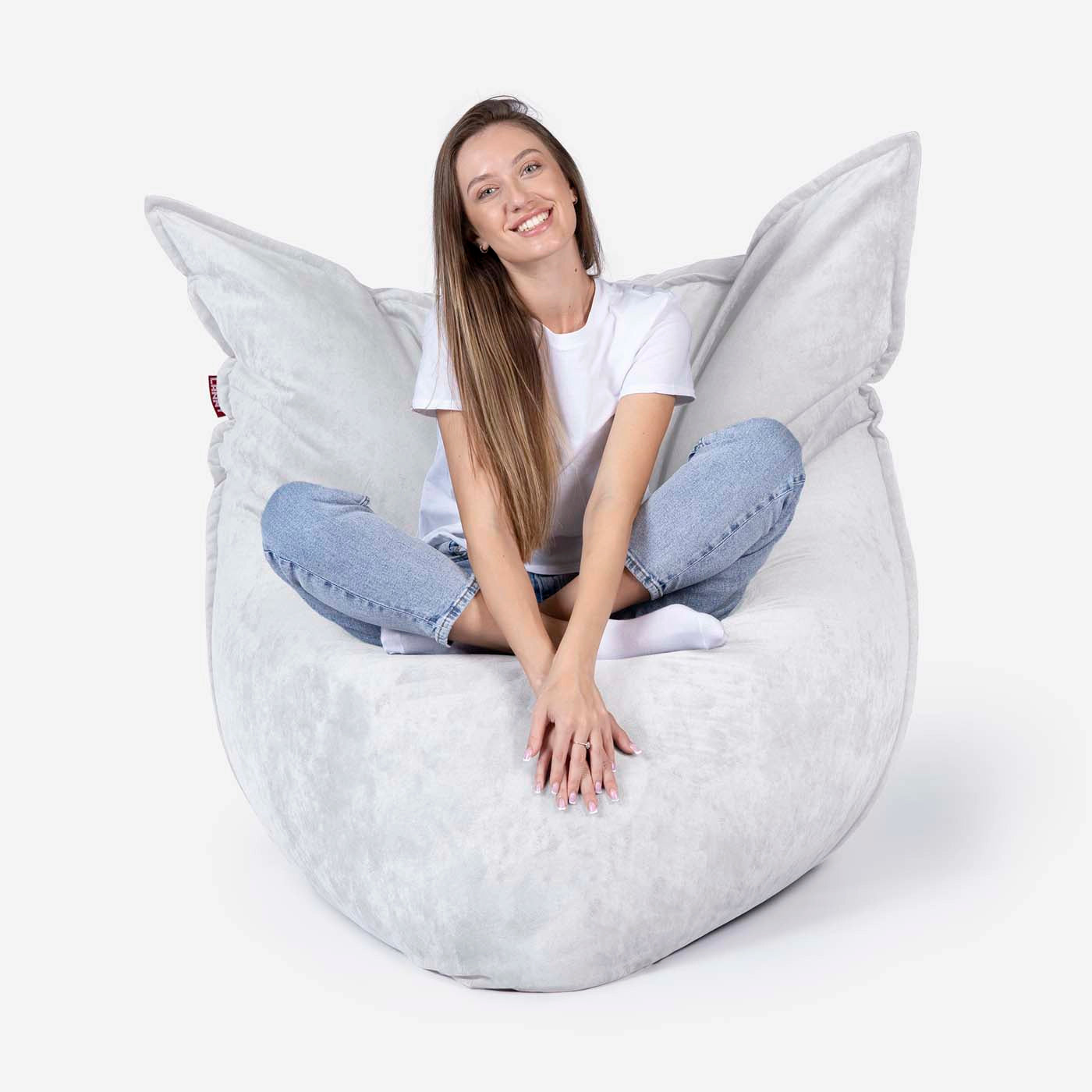 Woman sitting on a Lanny sloppy large bean bag chair on a white background