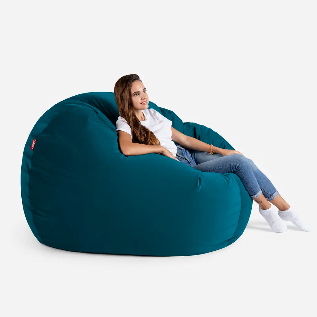 Woman relaxing on a Lanny Sphere Aqua Blue velvet bean bag chair, showing the large size and comfortable back support