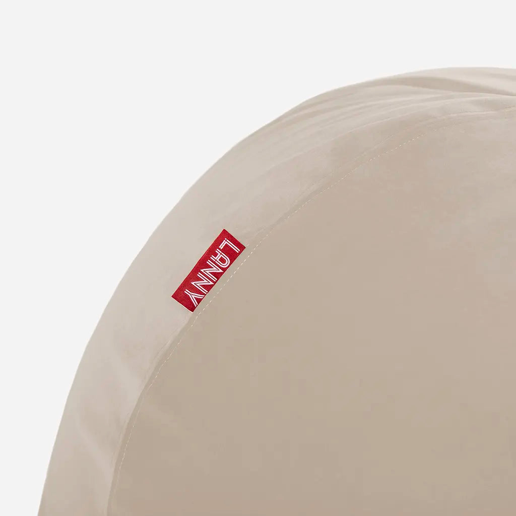 Close-up detail of the Lanny red brand tag and the ultra-soft texture of the beige velvet bean bag fabric