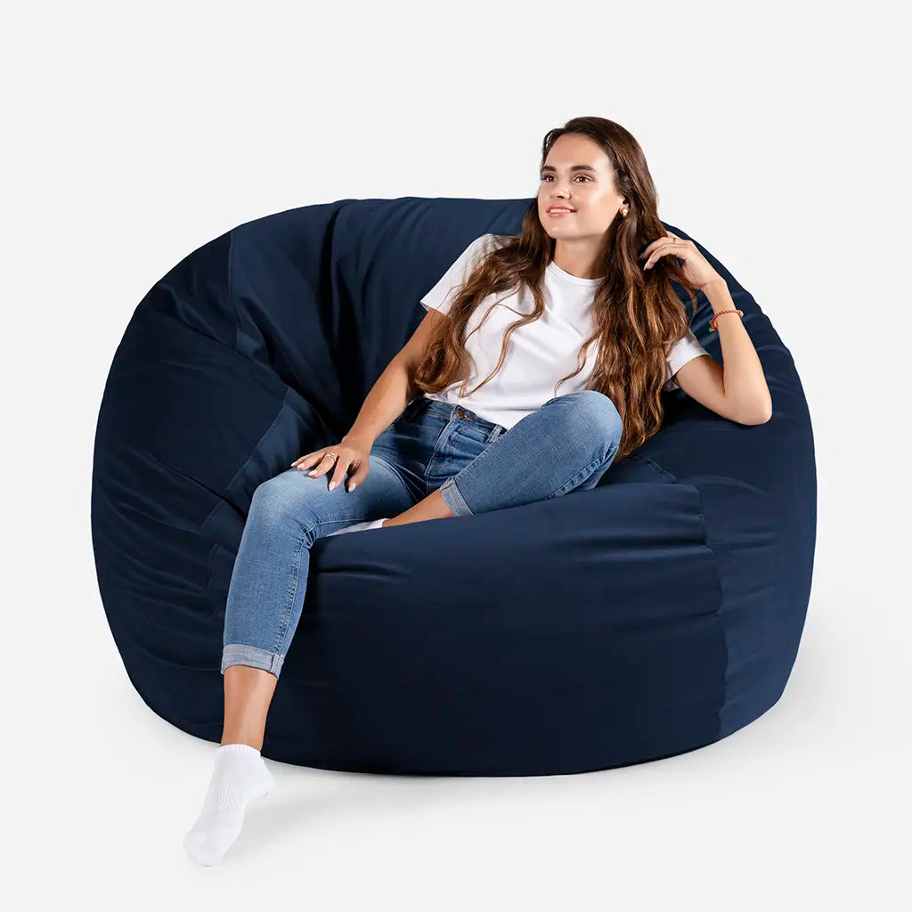Woman sitting comfortably on a Lanny Sphere oversized velvet bean bag chair in Blue color for UAE living room seating